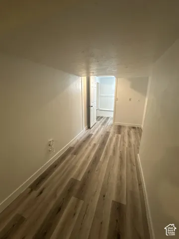 Wood-finish flooring throughout, white walls, and a white interior door