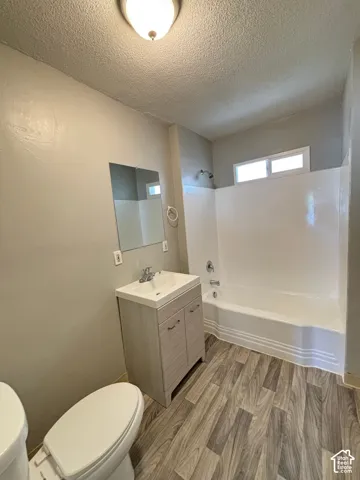 Updated bathroom featuring a wood-finish vanity with integrated sink, ceramic tile flooring, frameless glass shower enclosure, and recessed ceiling lighting