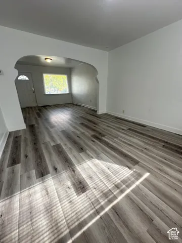 Wood-finish flooring throughout, arched entryway, and white painted walls