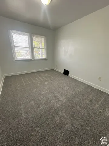 Bright, neutral bedroom with carpet flooring, large double-hung window with natural light, fresh paint, and ceiling fixture