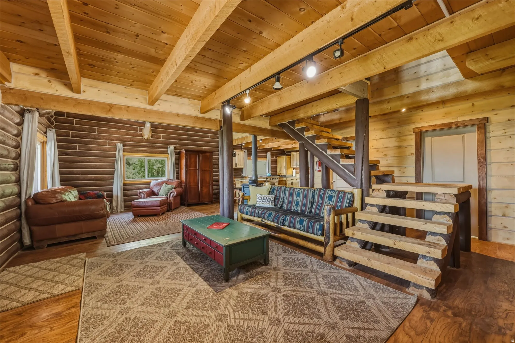 Exposed wood beam ceilings, wood-paneled walls, natural wood flooring, and a log staircase with track lighting