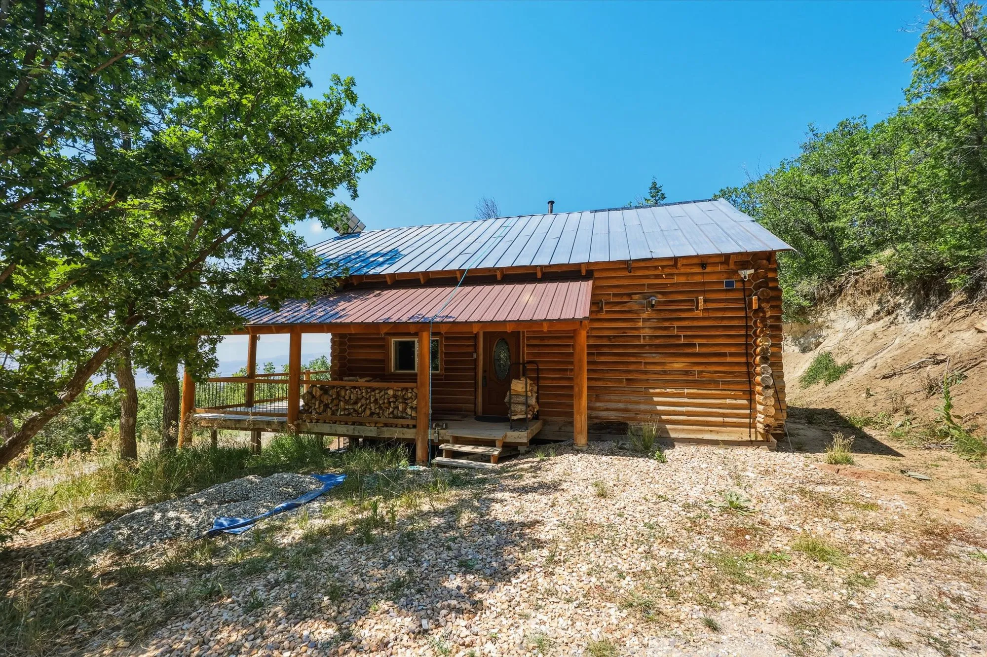 Log cabin exterior with a durable metal roof, covered porch, and natural wood siding