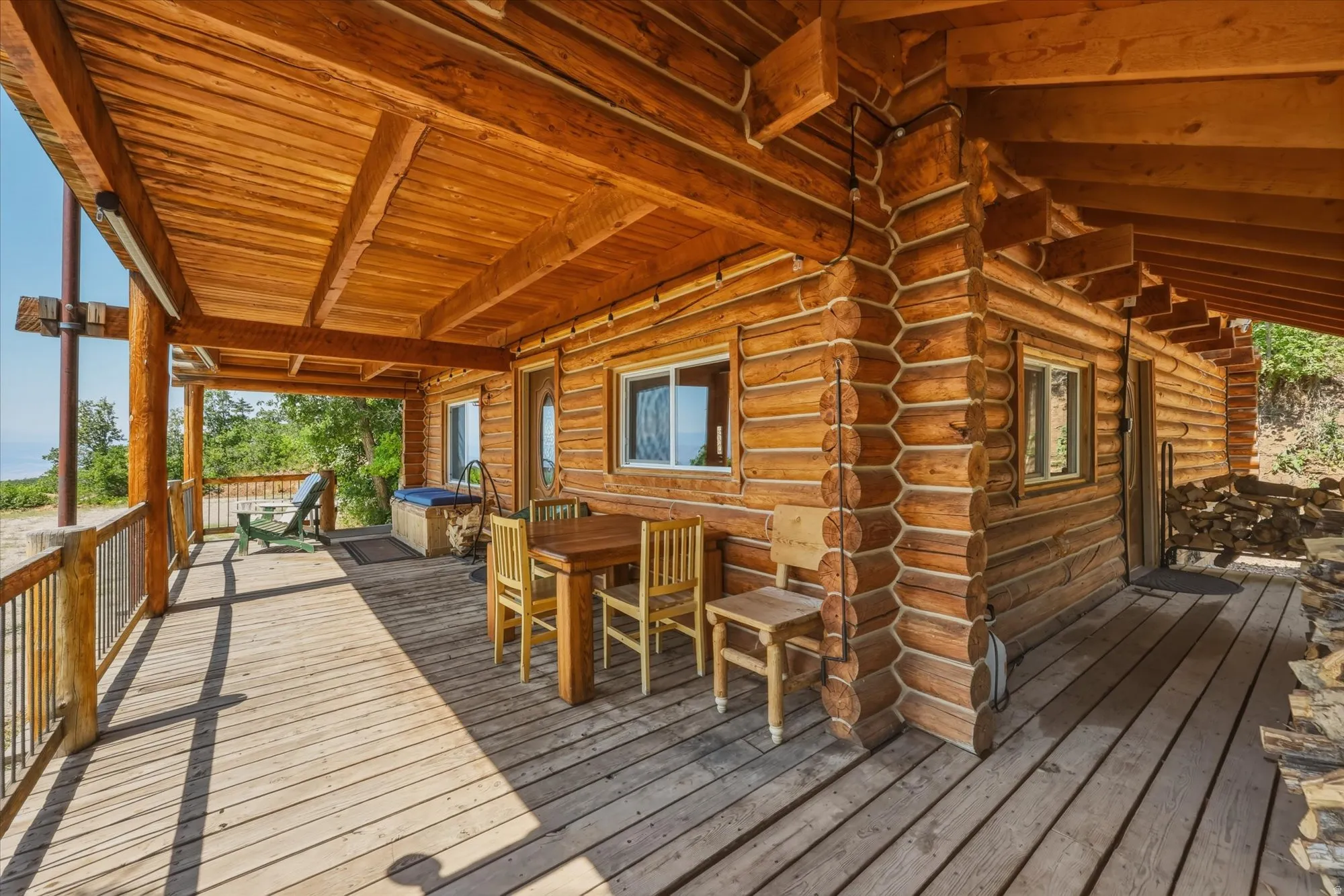 Expansive covered porch featuring wood flooring, wood post and beam construction, and a natural log exterior