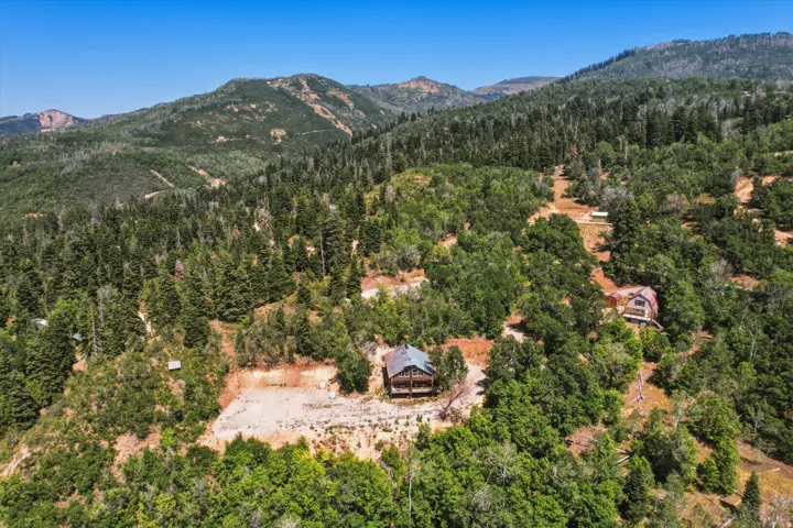 Mountainous terrain with dense forest, multiple structures, and cleared areas