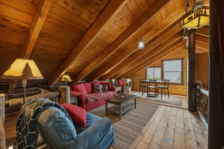Vaulted wood-paneled ceilings, exposed wood beams, wood-finish flooring, two windows, and built-in wood railings