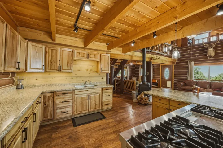 Kitchen featuring wood cabinetry, light-toned countertops, a stainless steel range, and wood-finish flooring