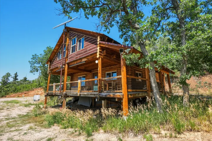 Log home exterior with a pitched roof, raised deck, and exposed wood beam construction