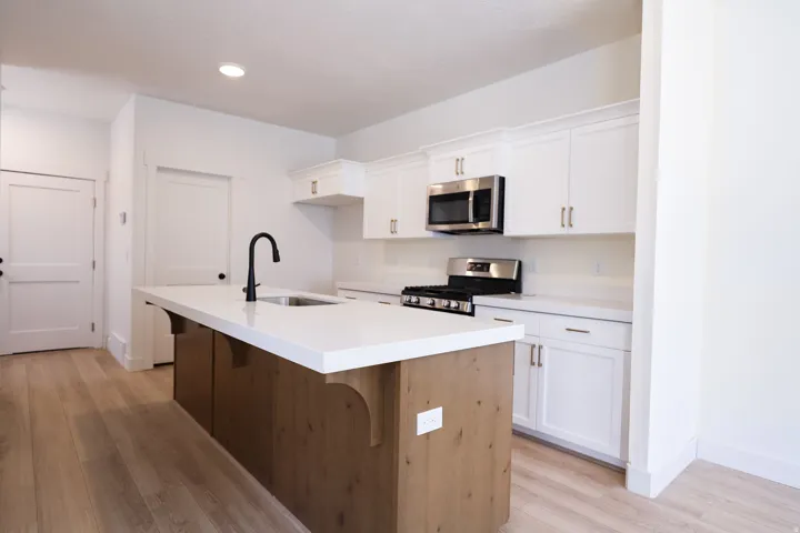 Terrific kitchen with painted white wood cabinets, stained wood island, quartz slab countertop, walk-in pantry, gas range, microwave, built-in dishwasher and disposal.