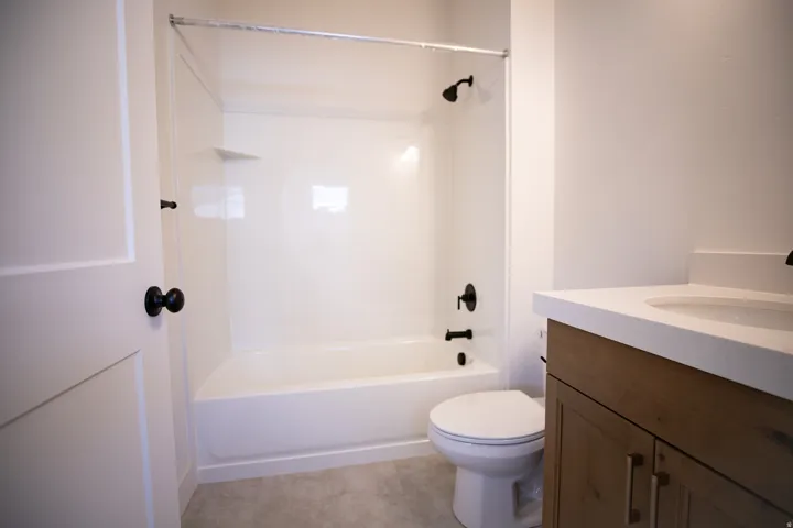 Full secondary bath with stained wood cabinets and quartz slab countertops.
