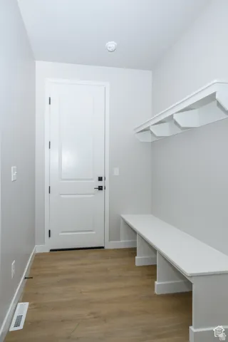 Wood-finish flooring, built-in storage bench, and white paneled door