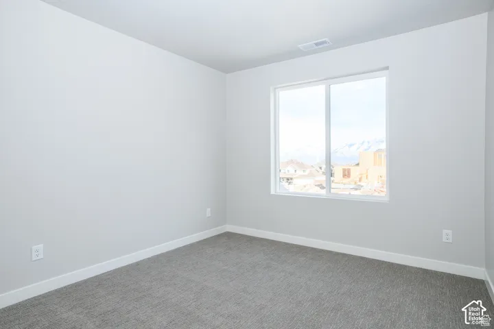 Window with mountain scenery, light gray wall paint, gray carpeting, white trim, and white electrical outlets