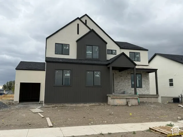 Contemporary exterior featuring a combination of vertical board siding, light-toned stucco, and stone veneer accents, complemented by a covered front porch and a multi-gabled roofline