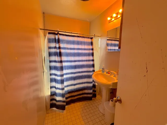 Pedestal sink with dual-handle faucet and wall-mounted mirror