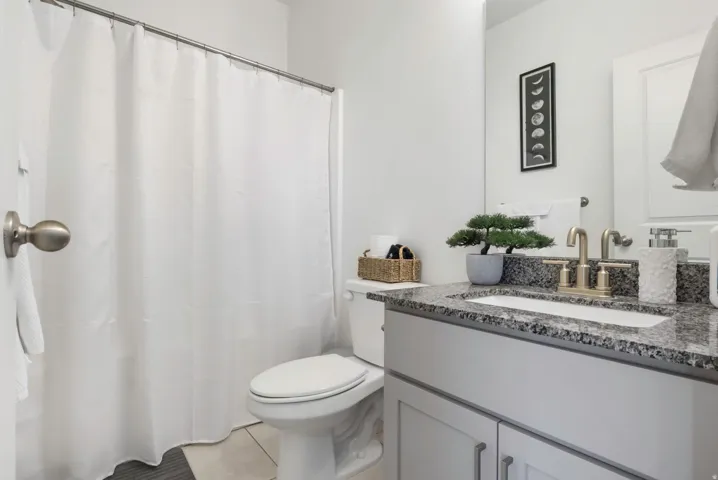 Vanity with a granite countertop, undermount sink, and brushed brass faucet