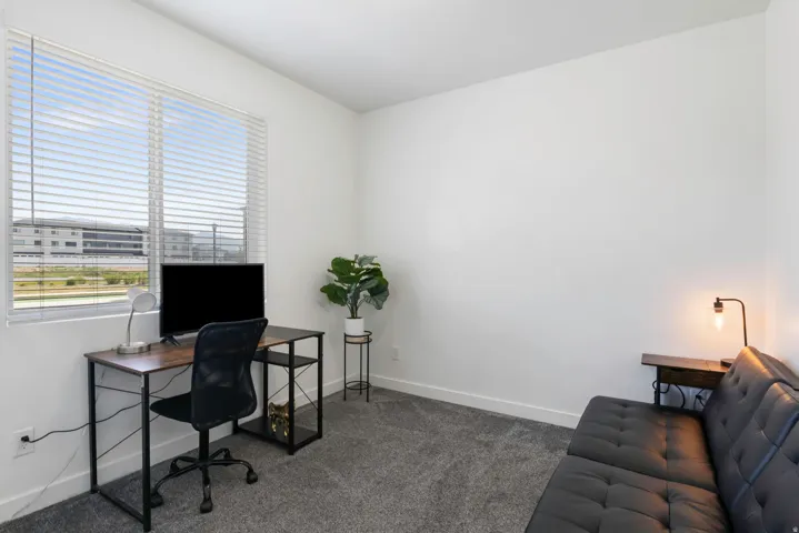 Large window with horizontal blinds, neutral wall paint, and gray carpet flooring