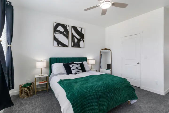 Room featuring a ceiling fan, white paneled door, and textured carpet