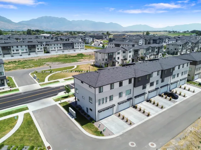 Townhome exterior with a dark shingle roof, light-toned siding, and attached garages