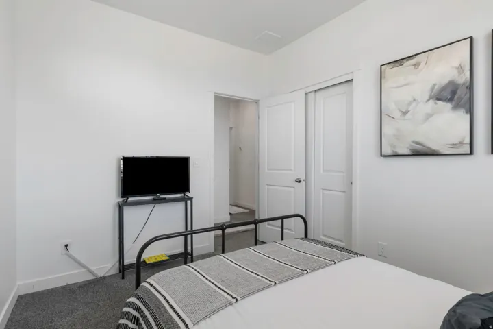 White painted walls, carpeted flooring, white trim, and a built-in closet with sliding doors
