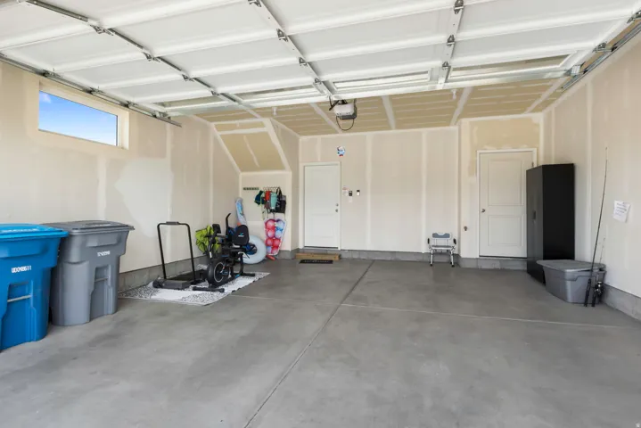 Expansive garage with a concrete floor, two white entry doors, and a high horizontal window