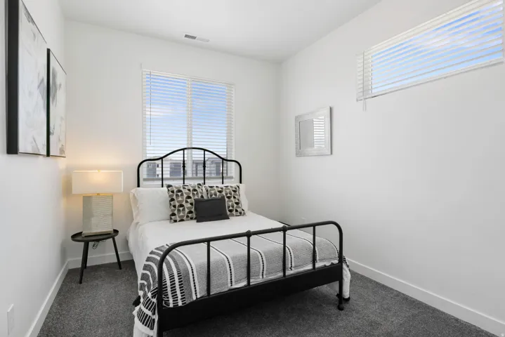 White walls, gray carpet, and two windows with horizontal blinds