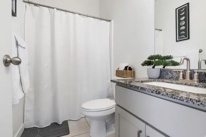 Bathroom featuring a single vanity with stone countertop, undermount sink, and brushed nickel faucet