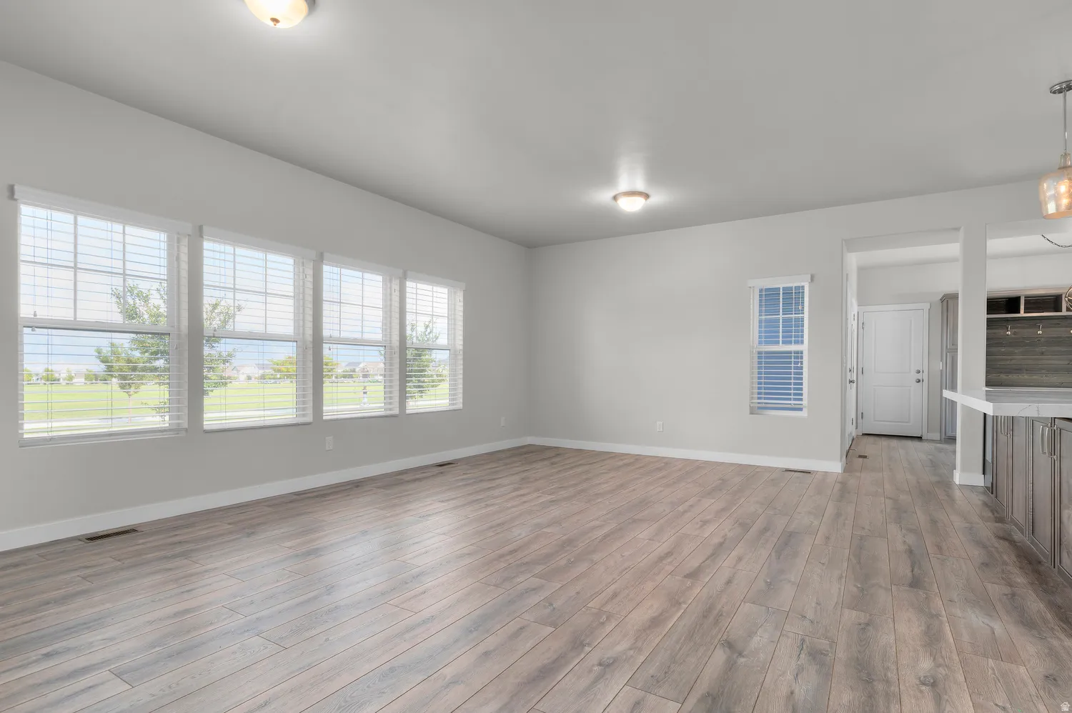 Open-concept living space with wood-finish flooring, multiple windows, and recessed lighting