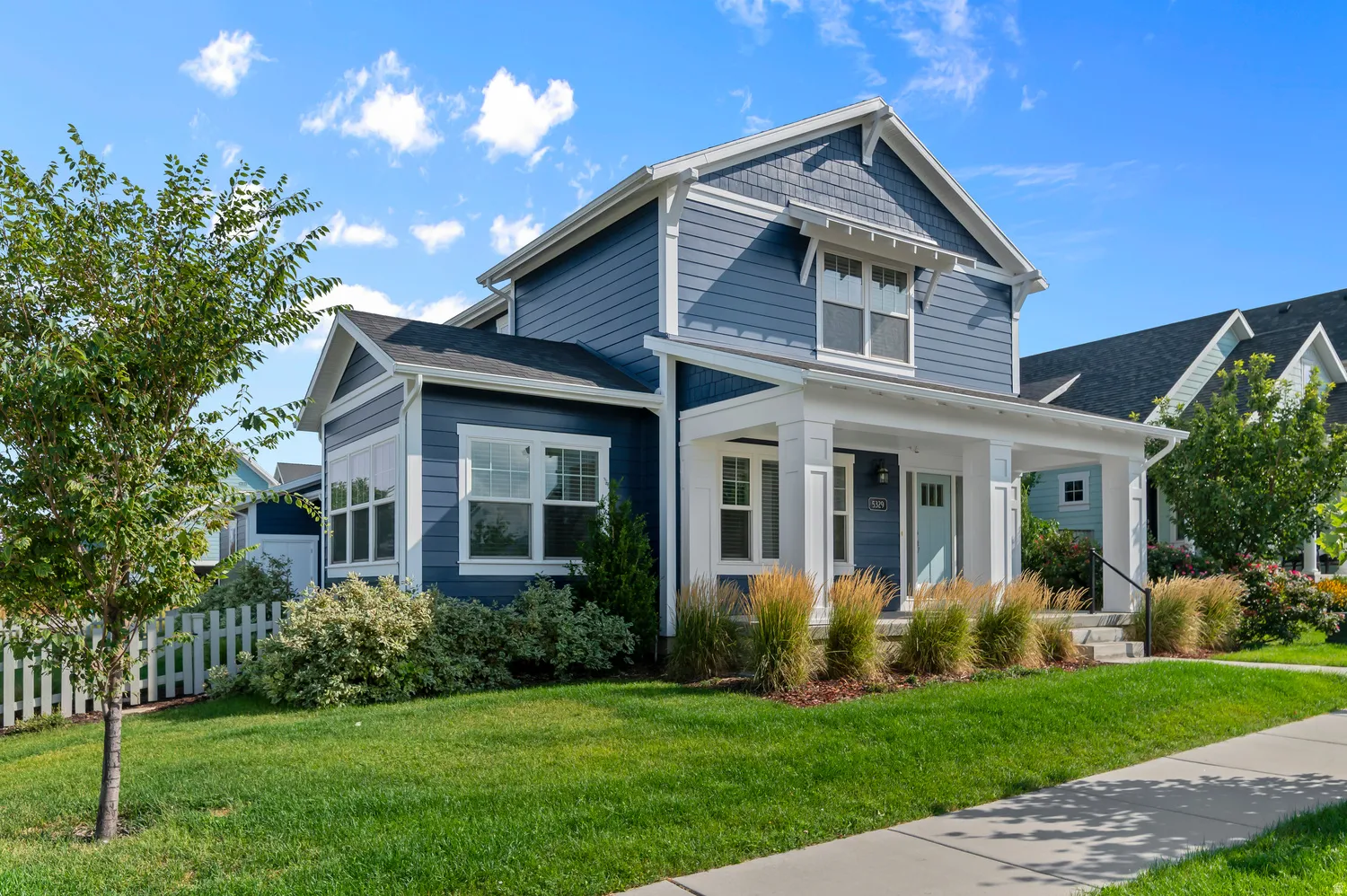 Exterior featuring blue horizontal siding, white trim, a covered front porch with white columns, and a light blue front door