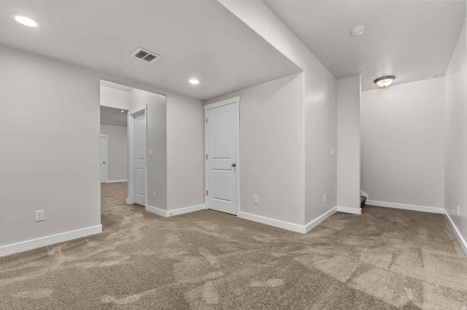 Neutral tone wall paint, recessed ceiling lighting, carpeted flooring, and white trim