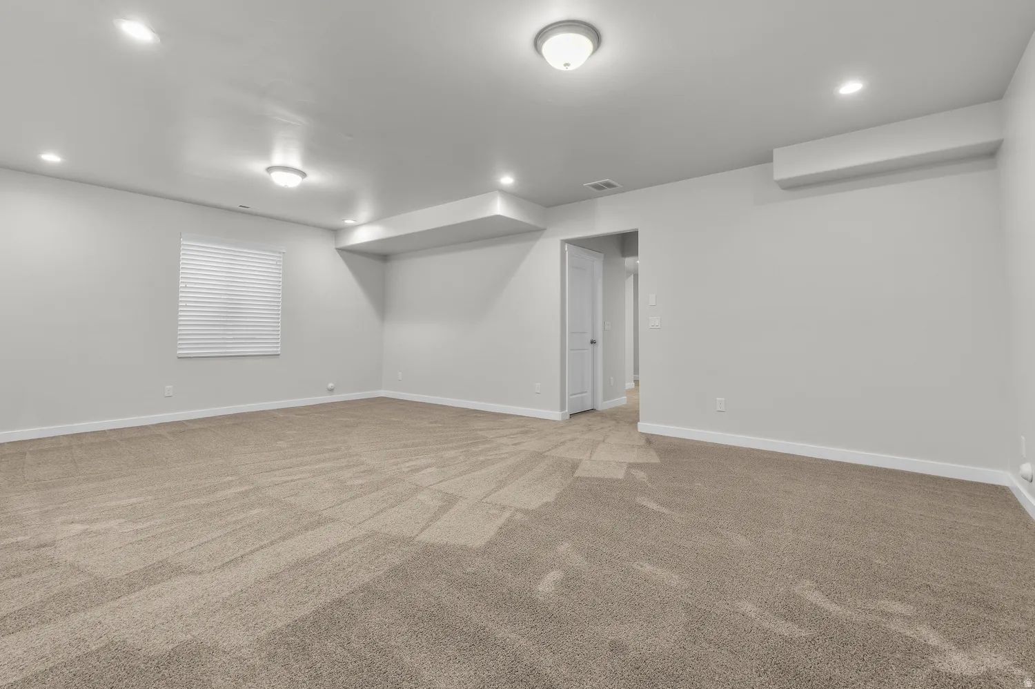 Spacious room featuring neutral carpeting and light-toned walls