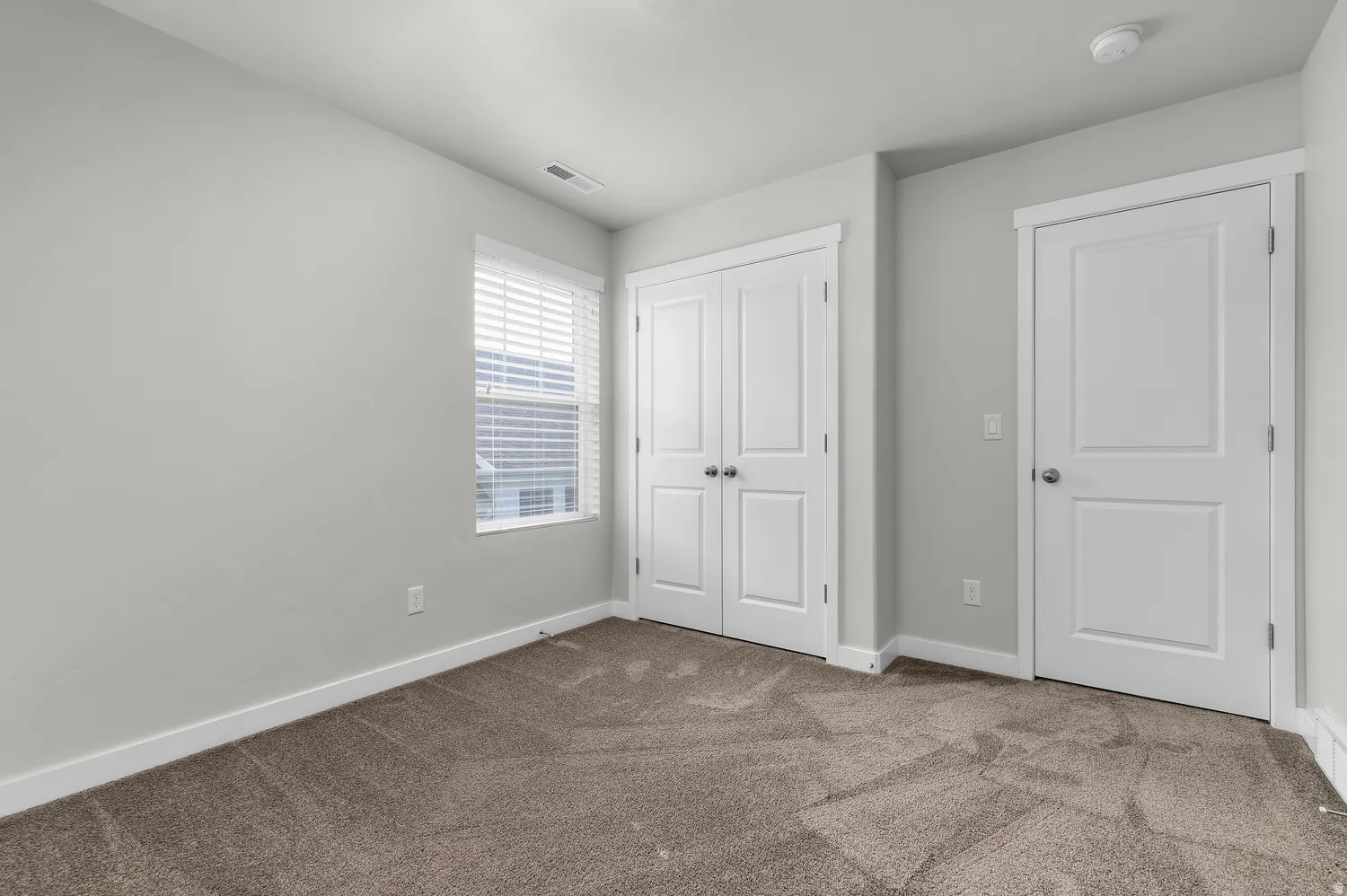 Wall-to-wall carpeting, window with blinds, and white trim throughout