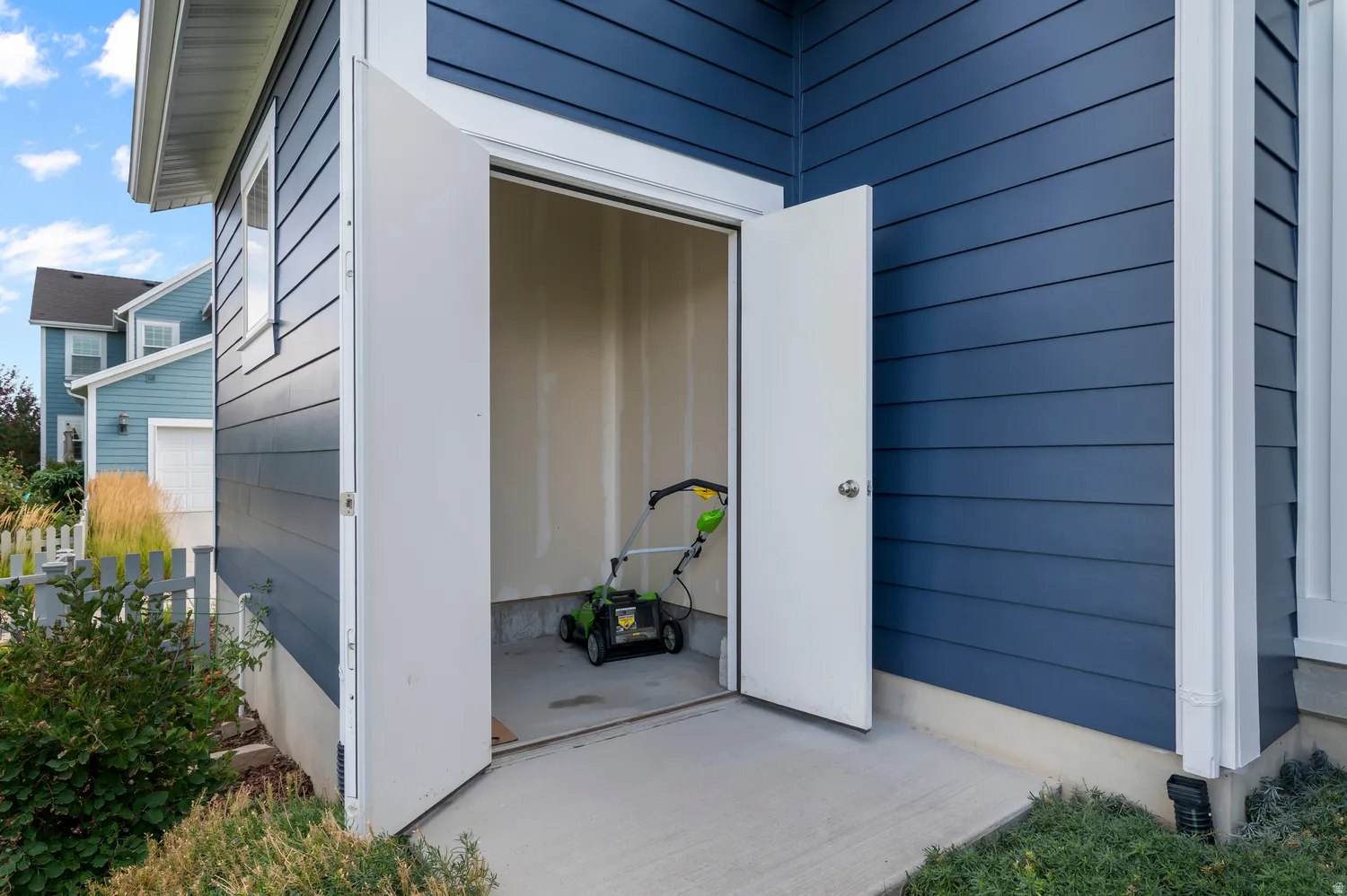 Exterior storage room with concrete flooring, double entry doors, and durable siding