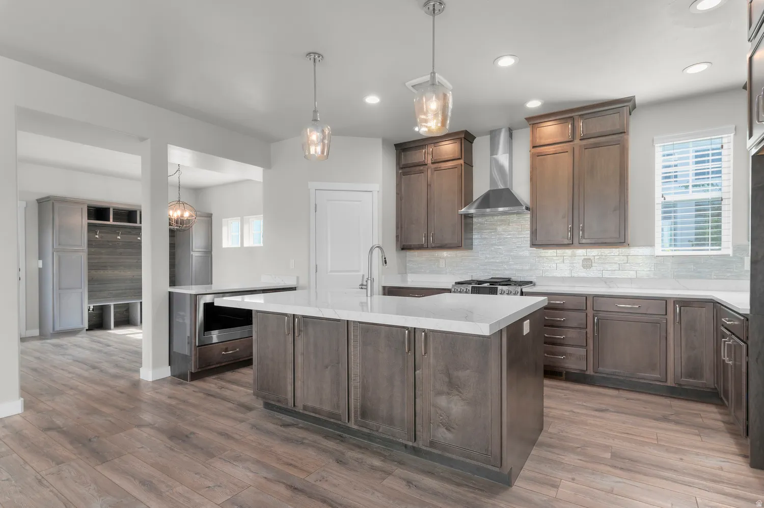 Kitchen featuring wood-finish flooring, dark wood cabinetry, white countertops, and a tile backsplash