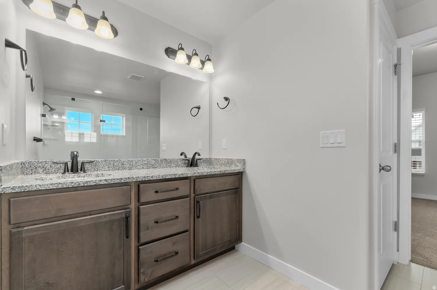 Dual vanity with granite countertops, undermount sinks, and dark wood-finish cabinetry