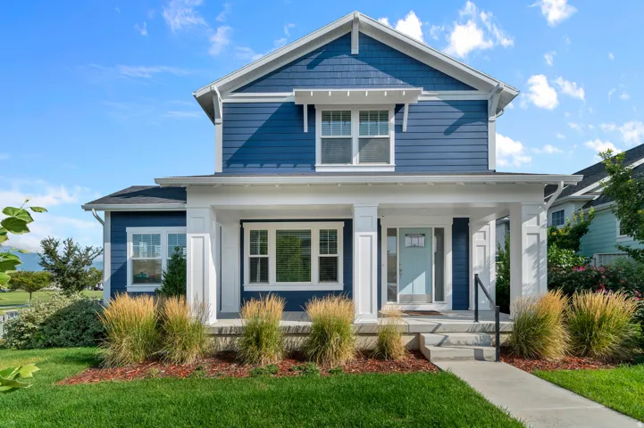 Two-story residence featuring blue siding, white trim, a covered front porch, and a light blue front door