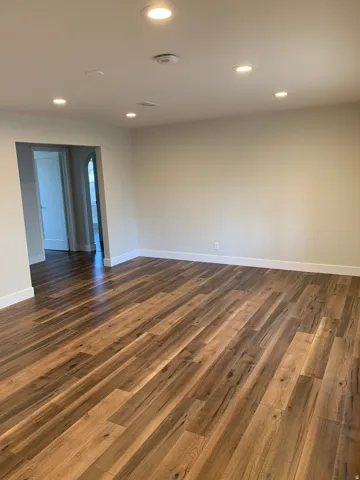 Wood-finish flooring, recessed lighting, neutral wall tones, and white trim
