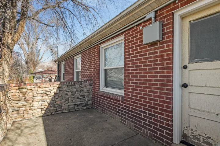 Brick exterior with multiple windows and a stone veneer retaining wall