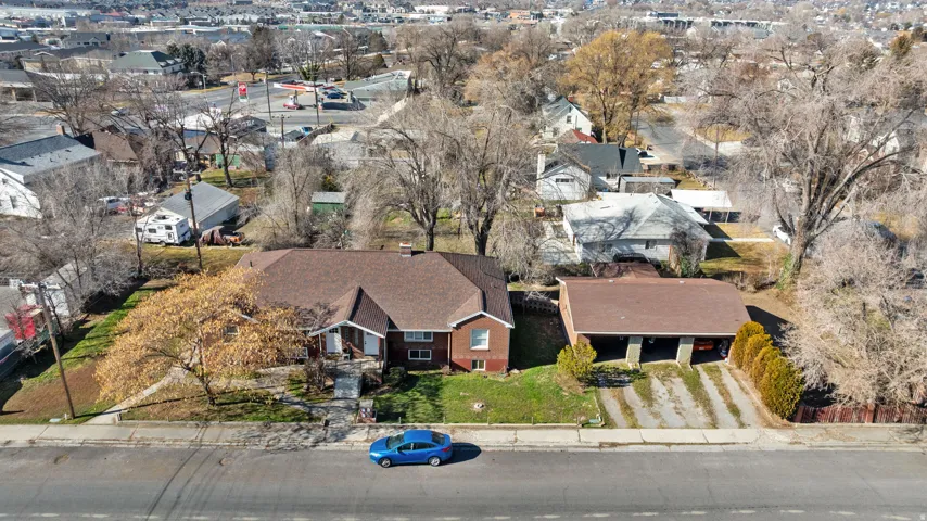 Brick exterior, multi-level home, covered front entry, two-car carport, and mature trees