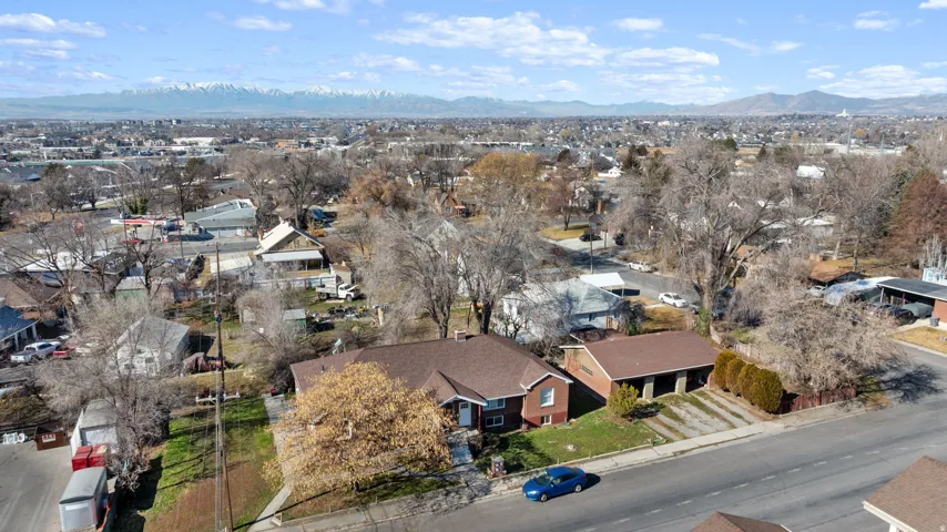 Brick exterior property with an attached garage, a spacious driveway, and mature trees, set against a distant mountain range