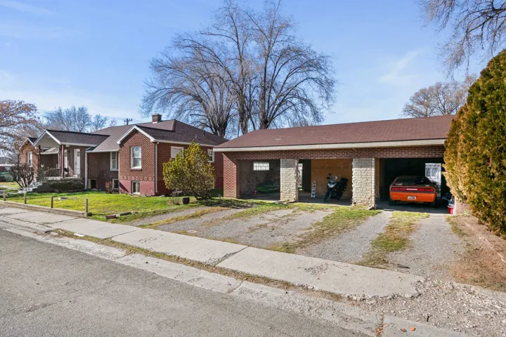 Brick exterior residence with a covered carport featuring multiple bays and a paved driveway