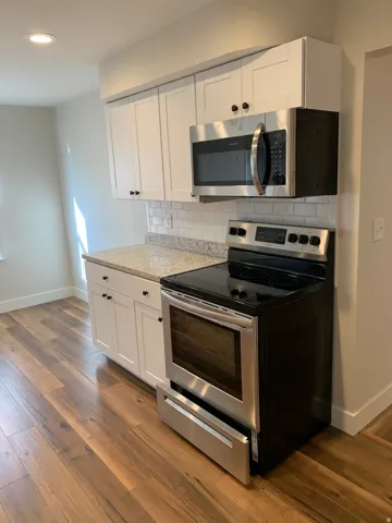 White cabinetry with black hardware, complementing granite-style countertops, stainless steel appliances, and a subway tile backsplash