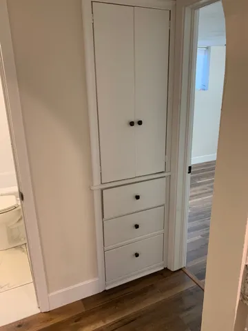 Built-in storage cabinet with three drawers and upper double-door cabinetry, featuring matte black hardware
