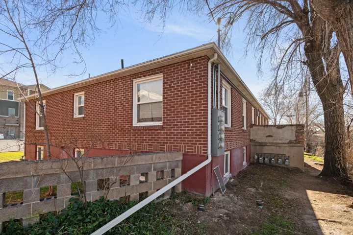 Brick exterior with multiple windows and a concrete block wall