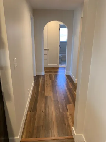 Wood-finish flooring throughout, arched doorway, and built-in cabinetry