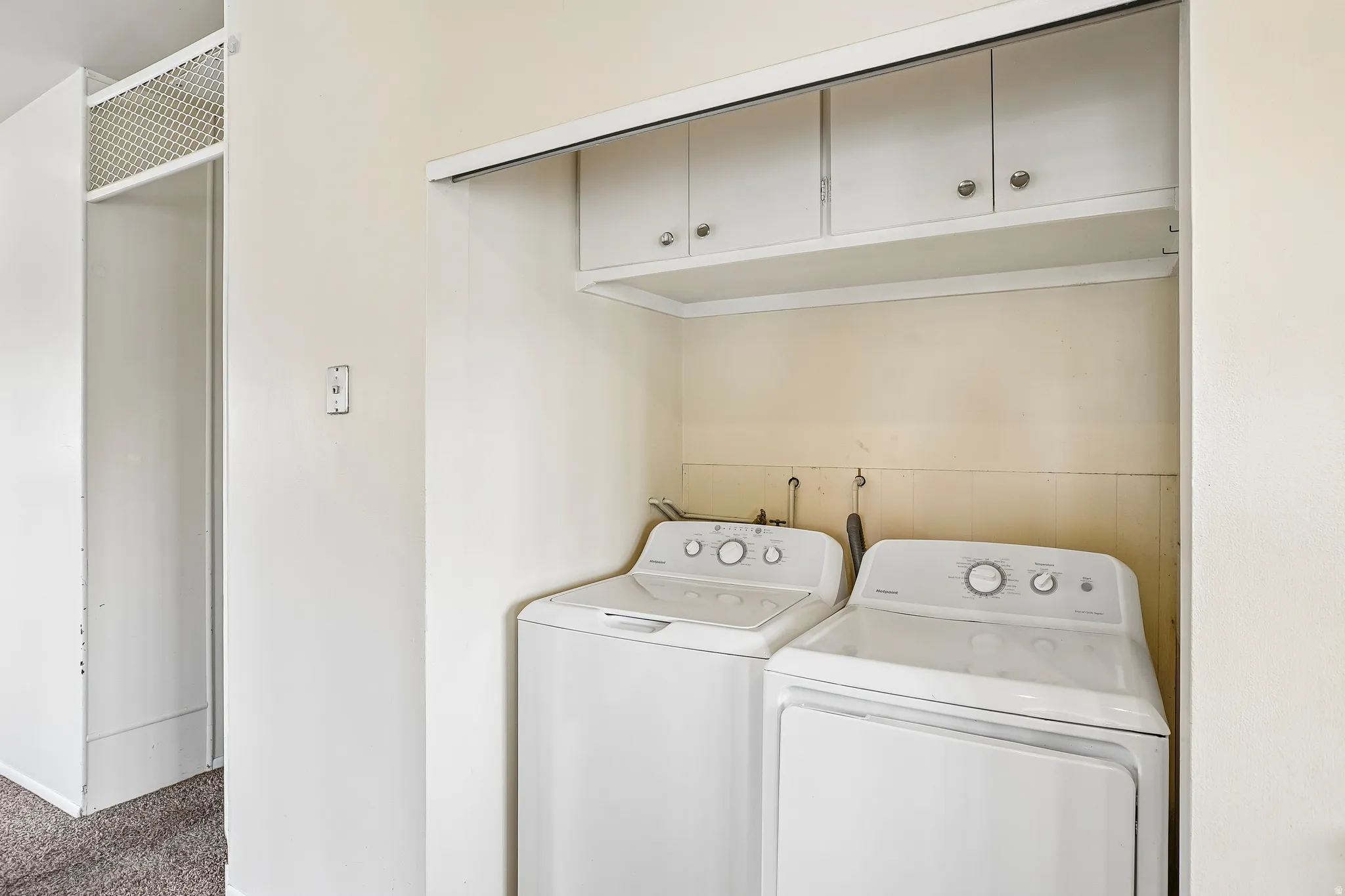 Laundry area with overhead white cabinetry and wall-mounted plumbing
