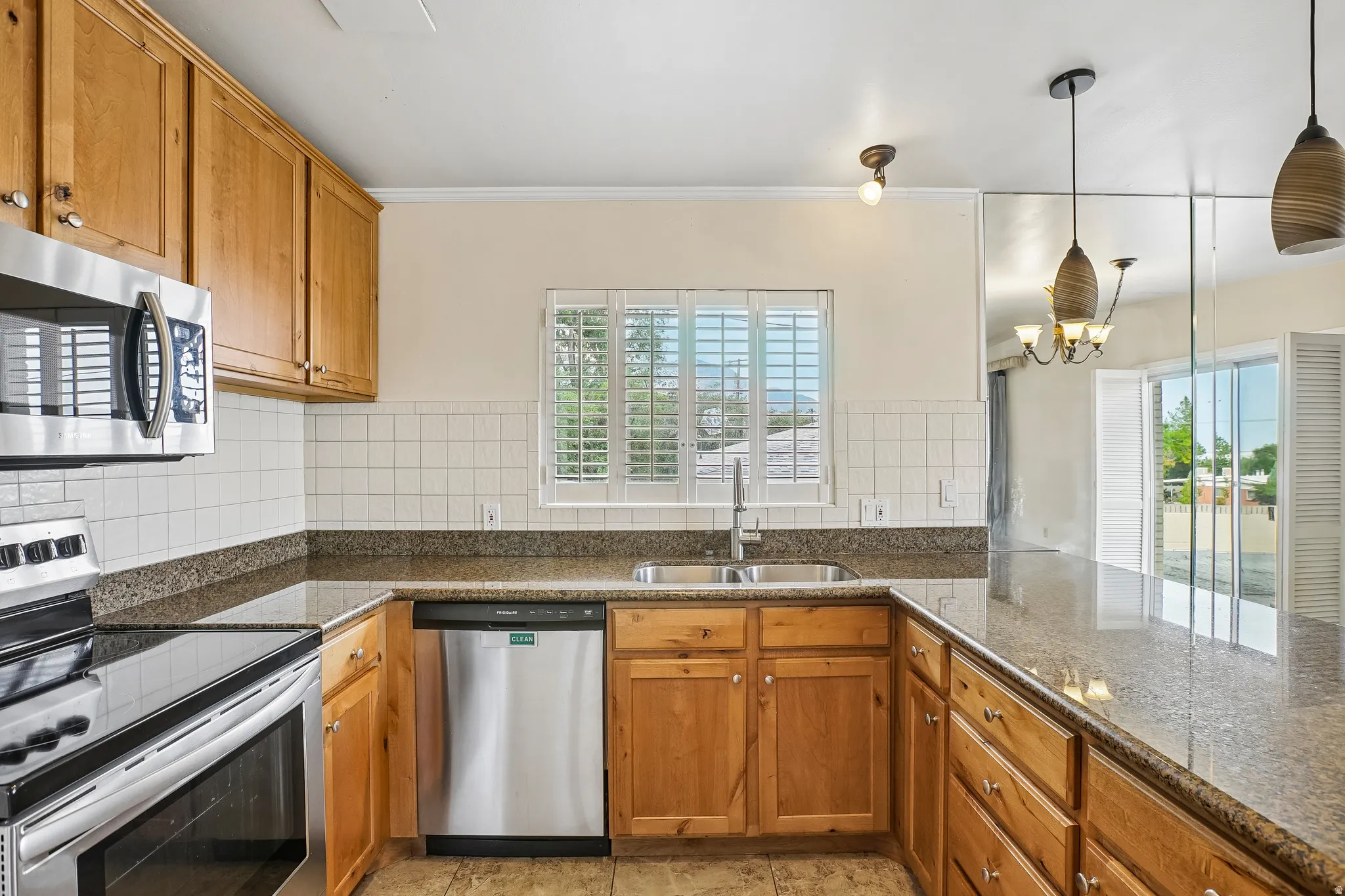 U-shaped kitchen featuring wood cabinetry, stainless steel appliances, and a tile backsplash