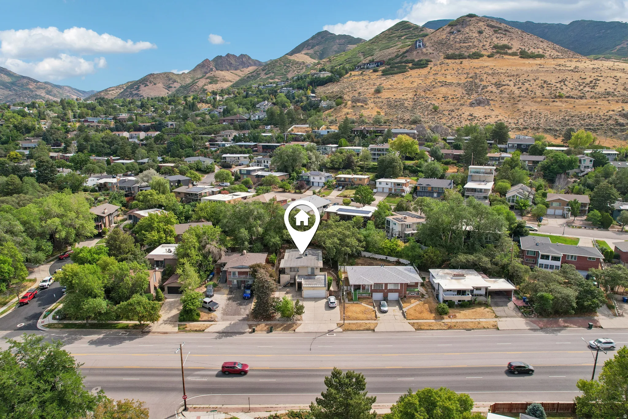 Aerial perspective showcasing a residential area with mature trees and mountain backdrops