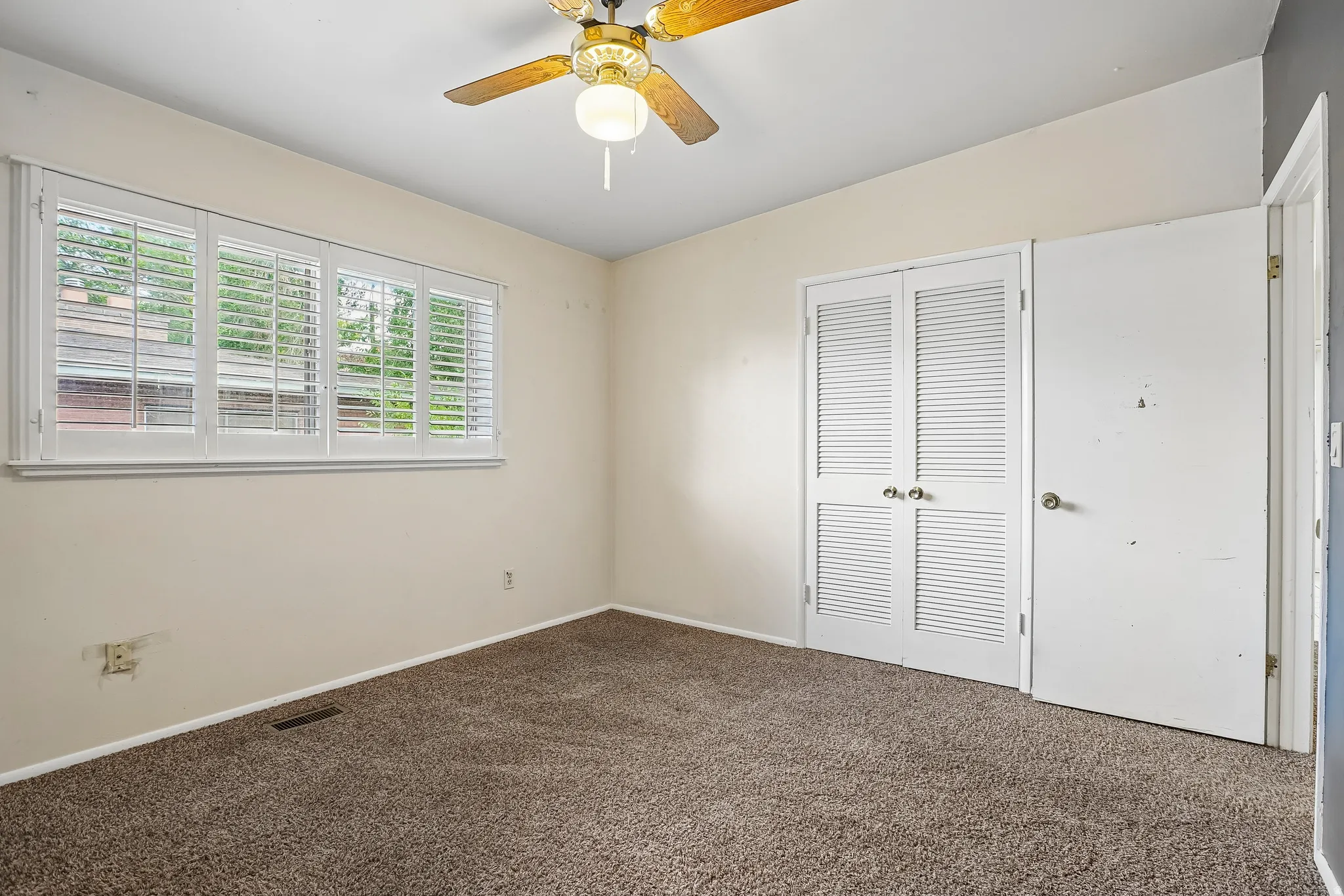 Carpet flooring, white plantation shutters, louvered bi-fold doors, and a ceiling fan with light fixture