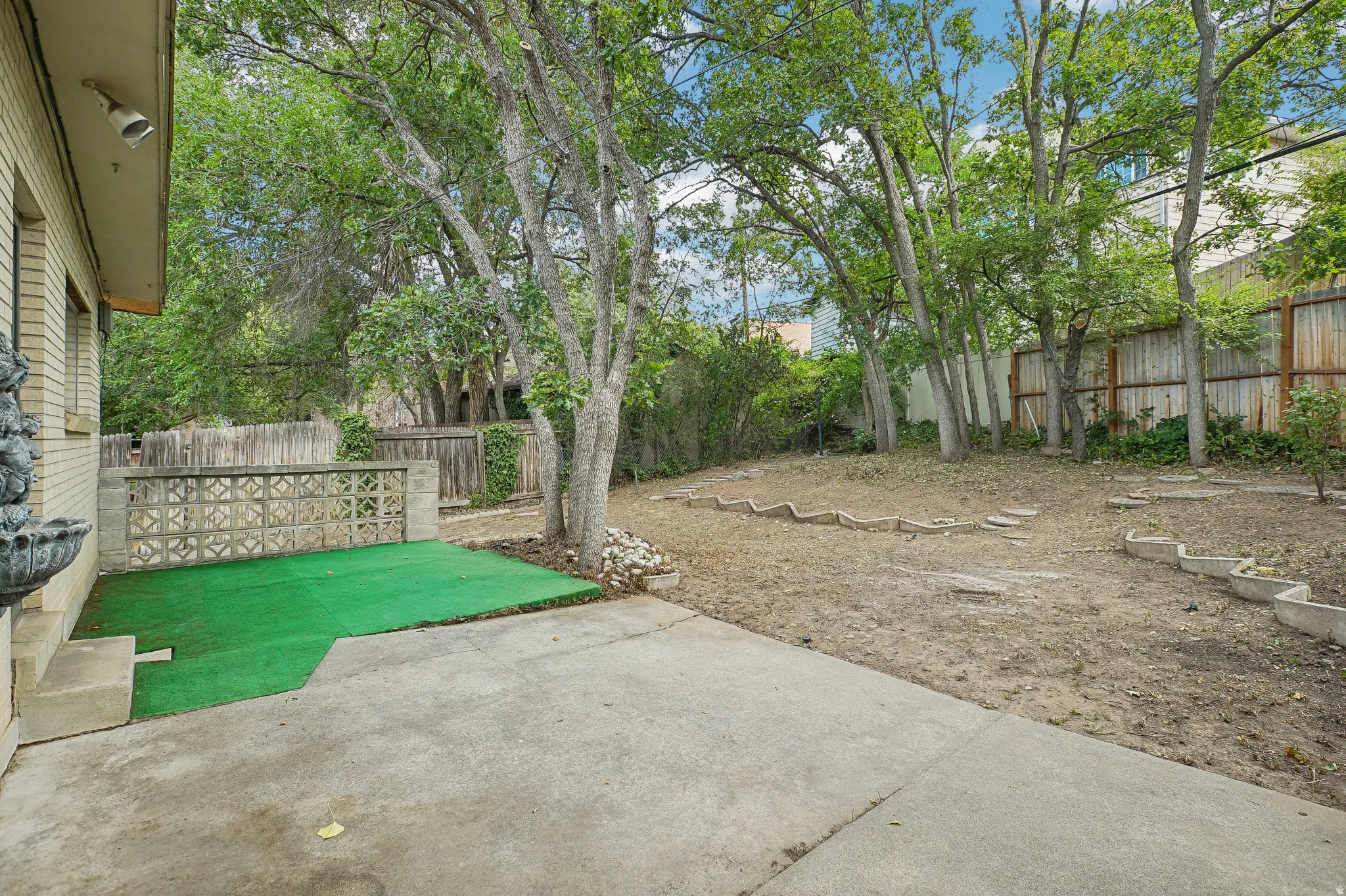 Concrete patio leading to a raised green-turfed area