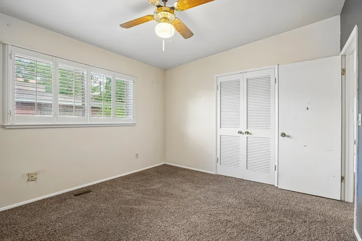 Carpet flooring, white plantation shutters, louvered bi-fold doors, and a ceiling fan with light fixture