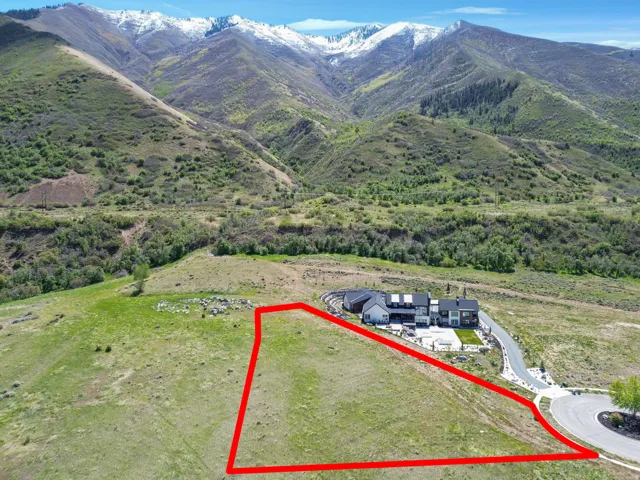 Expansive land parcel with surrounding mountain scenery and access to a paved road